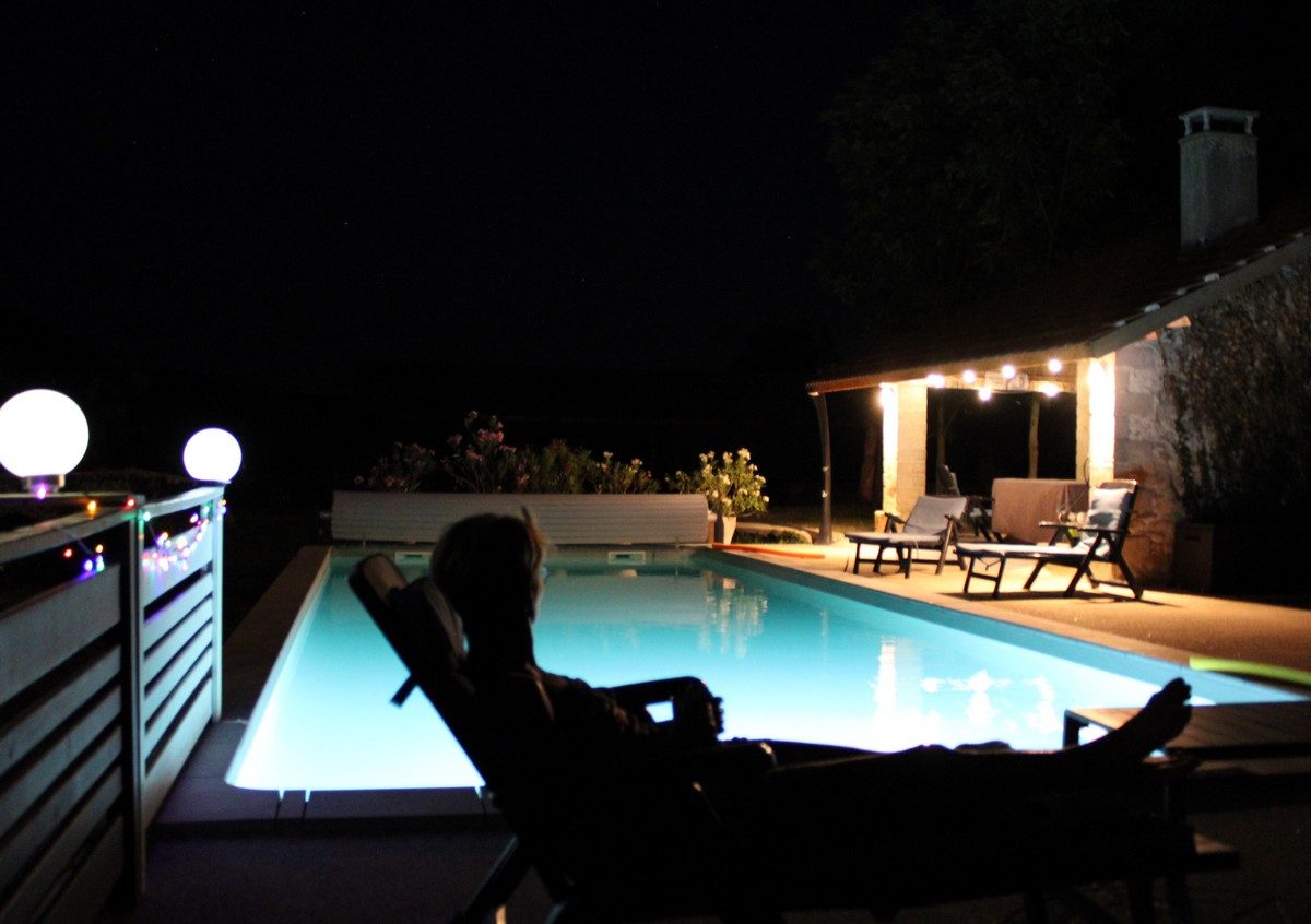 La piscine éclairée le soir, devant le pool house