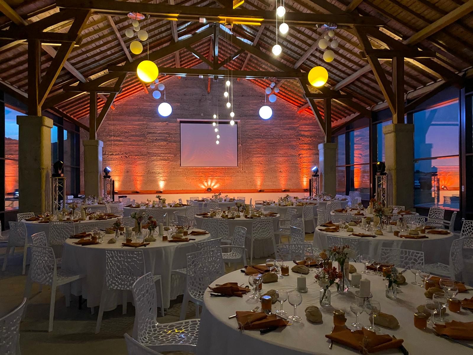 La salle dressée de tables rondes, lumières orangées