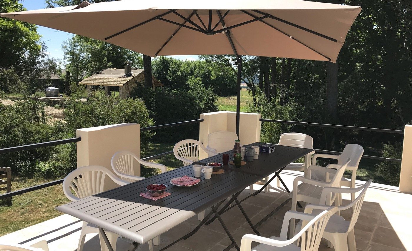 La terrasse dressée pour un repas, à l’ombre du parasol